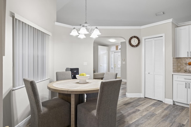 dining space featuring light hardwood / wood-style floors, an inviting chandelier, and crown molding