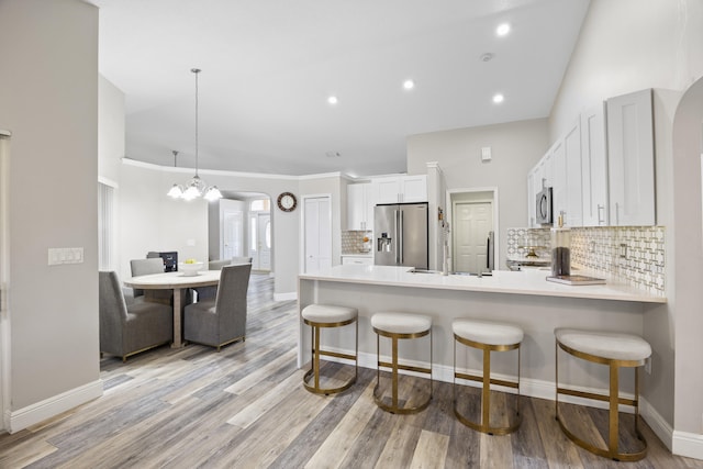 kitchen featuring appliances with stainless steel finishes, a peninsula, backsplash, light countertops, and recessed lighting