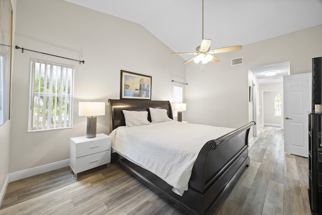 bedroom with multiple windows, lofted ceiling, wood finished floors, baseboards, and a ceiling fan
