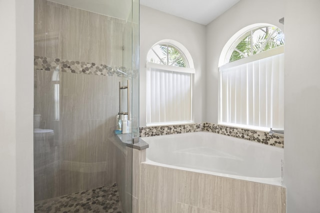 full bathroom with a tile shower and a bath
