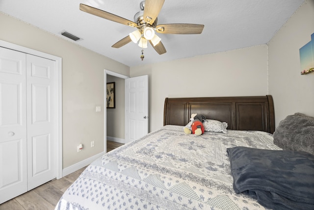 bedroom with light wood-type flooring, ceiling fan, and a closet