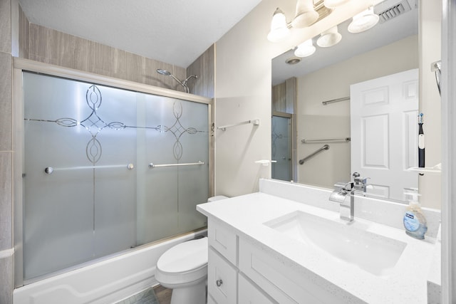 full bathroom with a textured ceiling, vanity, combined bath / shower with glass door, and toilet