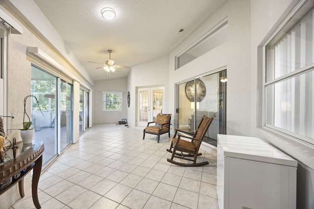 living area featuring light tile patterned flooring, ceiling fan, a textured ceiling, lofted ceiling, and french doors