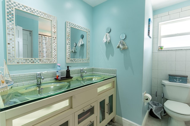 bathroom with toilet, vanity, and tile walls