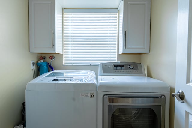 washroom featuring cabinets, washer and clothes dryer, and a wealth of natural light