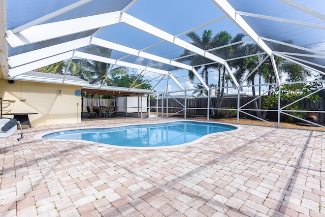 view of pool with a patio, glass enclosure, and a shed