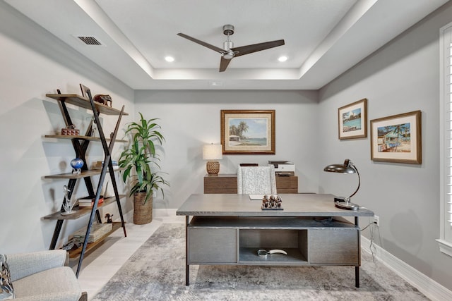 office space with ceiling fan and a tray ceiling