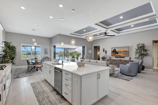 kitchen with hanging light fixtures, coffered ceiling, white cabinets, light hardwood / wood-style flooring, and a center island with sink