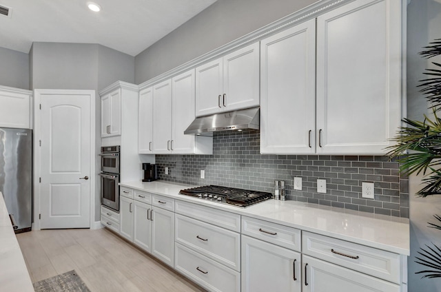 kitchen with white cabinetry, stainless steel appliances, backsplash, and light hardwood / wood-style floors