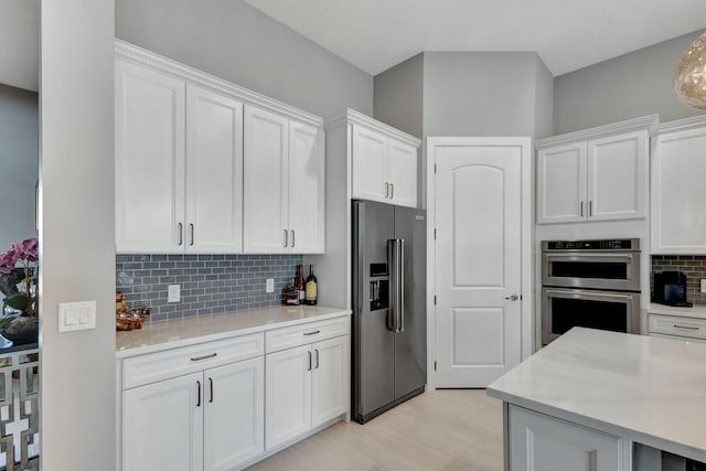 kitchen featuring decorative backsplash, white cabinets, light hardwood / wood-style flooring, and stainless steel appliances