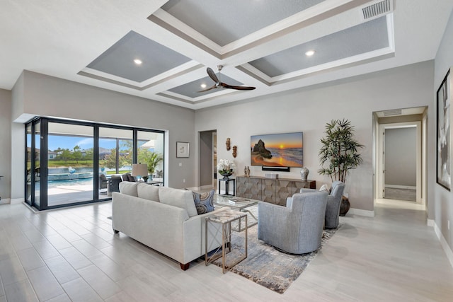 living room with a towering ceiling, light wood-type flooring, ceiling fan, coffered ceiling, and beamed ceiling