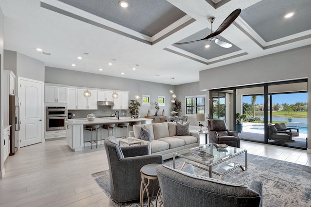 living room featuring ornamental molding, beamed ceiling, coffered ceiling, and light wood-type flooring