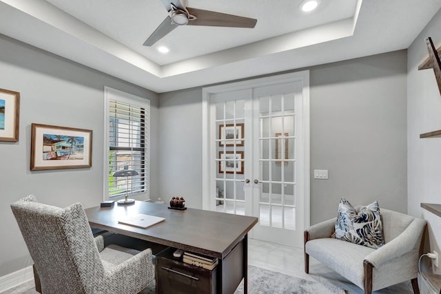 home office with light hardwood / wood-style flooring, french doors, a tray ceiling, and ceiling fan