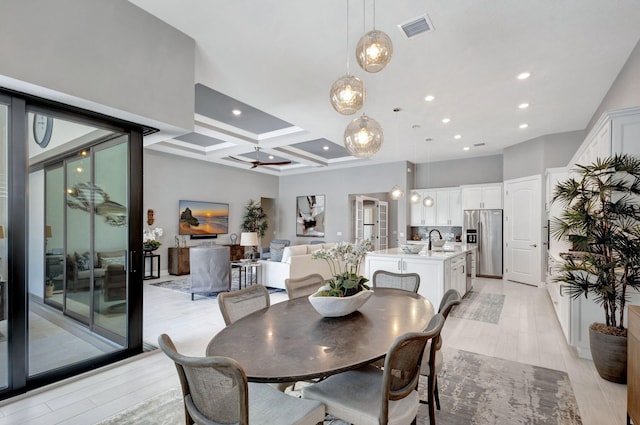 dining room with coffered ceiling, beam ceiling, sink, light hardwood / wood-style floors, and ceiling fan