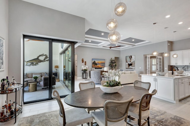 dining room featuring coffered ceiling, beamed ceiling, sink, and light wood-type flooring