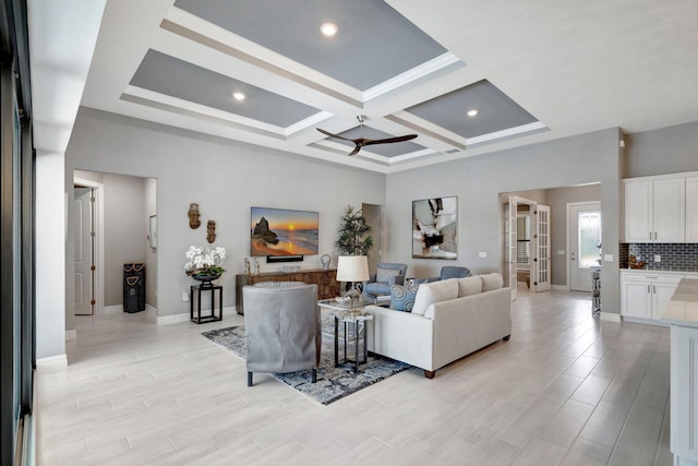 living room with beamed ceiling, coffered ceiling, light wood-type flooring, and ceiling fan