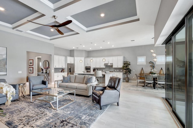 living room with beam ceiling, coffered ceiling, ornamental molding, and ceiling fan