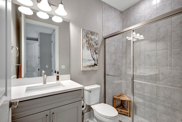 bathroom with a shower with door, vanity, and toilet