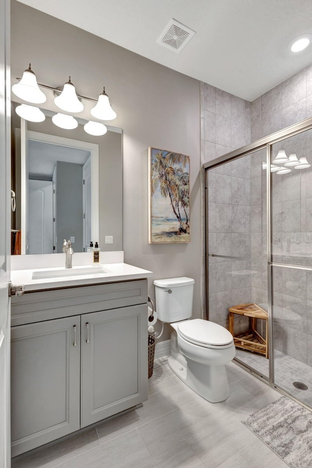 bathroom featuring toilet, vanity, and a shower with door