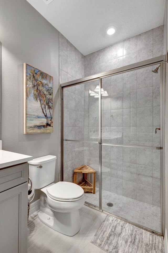 bathroom with toilet, a shower with shower door, and vanity