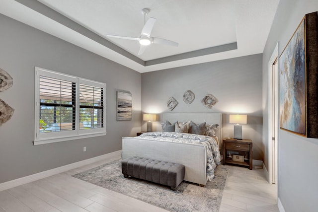 bedroom featuring light hardwood / wood-style floors, a raised ceiling, and ceiling fan