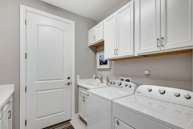 clothes washing area with cabinets, a textured ceiling, sink, and washing machine and dryer