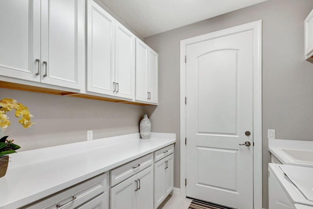 laundry area featuring washer / dryer, a textured ceiling, and cabinets