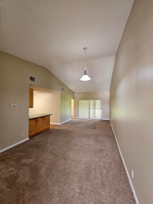 unfurnished living room featuring dark carpet, lofted ceiling, and a textured ceiling