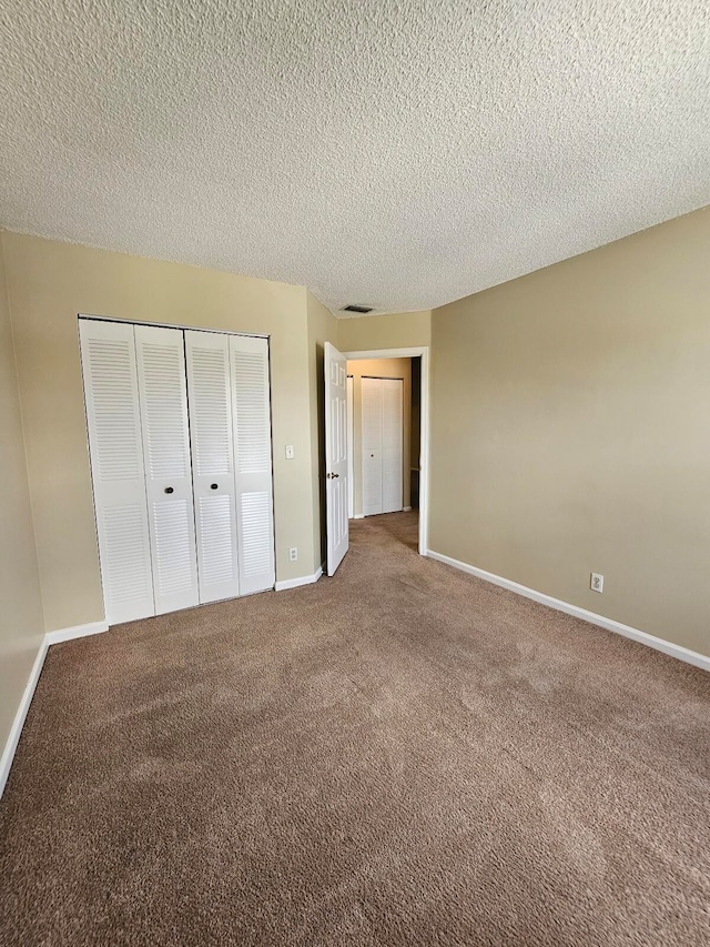 unfurnished bedroom featuring a textured ceiling, carpet flooring, and a closet