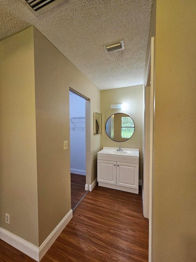 hallway with sink, dark wood-type flooring, and a textured ceiling