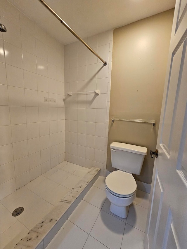 bathroom with toilet, tile patterned flooring, and tiled shower