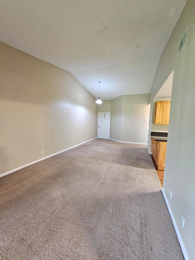 carpeted spare room with a textured ceiling and vaulted ceiling