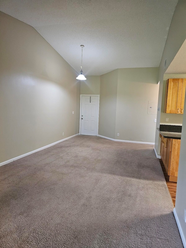 interior space featuring a textured ceiling, lofted ceiling, and light colored carpet