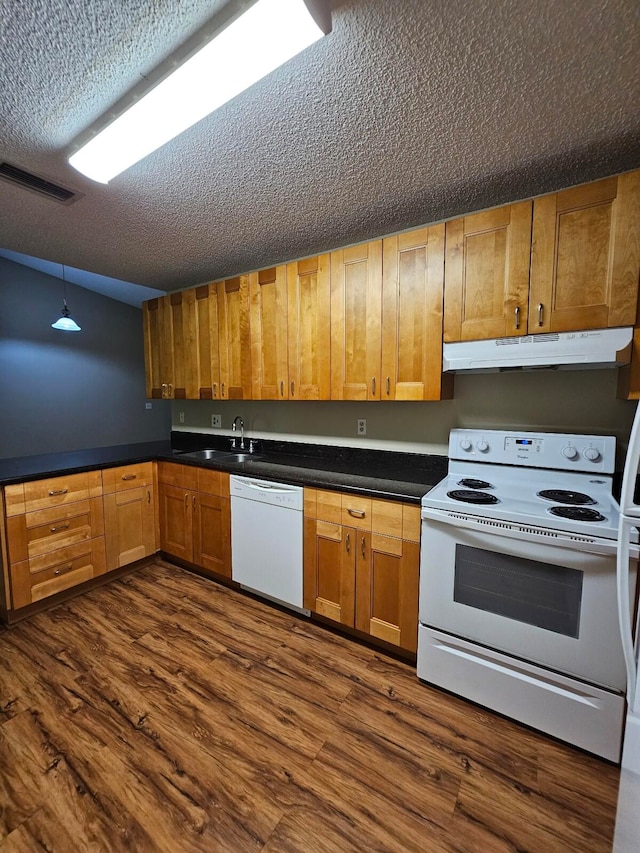 kitchen with hanging light fixtures, a textured ceiling, dark hardwood / wood-style floors, sink, and white appliances