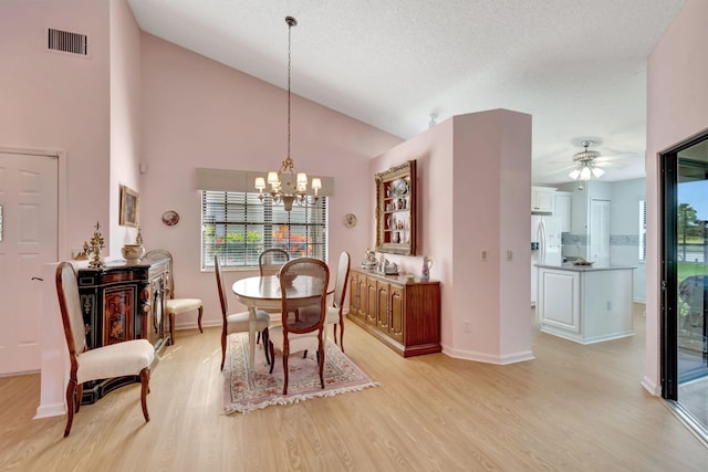 dining room with high vaulted ceiling, a textured ceiling, ceiling fan with notable chandelier, and light hardwood / wood-style floors