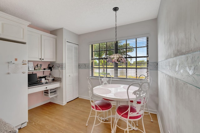 dining area with a textured ceiling and light wood-type flooring