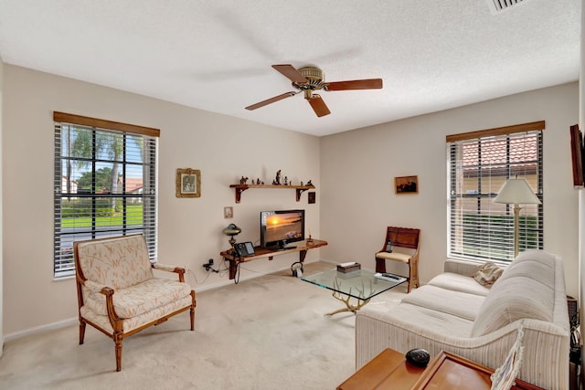 living area featuring light carpet, a textured ceiling, and ceiling fan