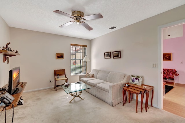 living room featuring light carpet, a textured ceiling, and ceiling fan