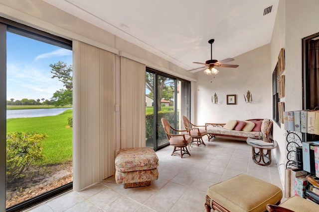 living room with a water view, ceiling fan, lofted ceiling, and light tile patterned flooring