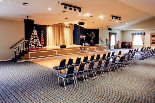 carpeted cinema room with lofted ceiling and rail lighting