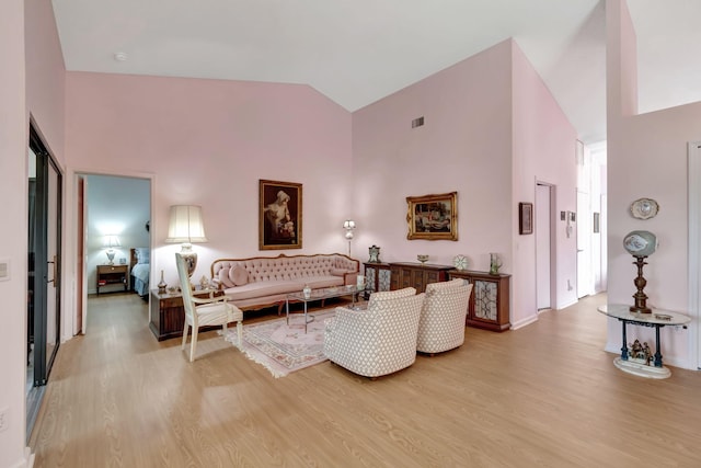 living room with high vaulted ceiling and light wood-type flooring