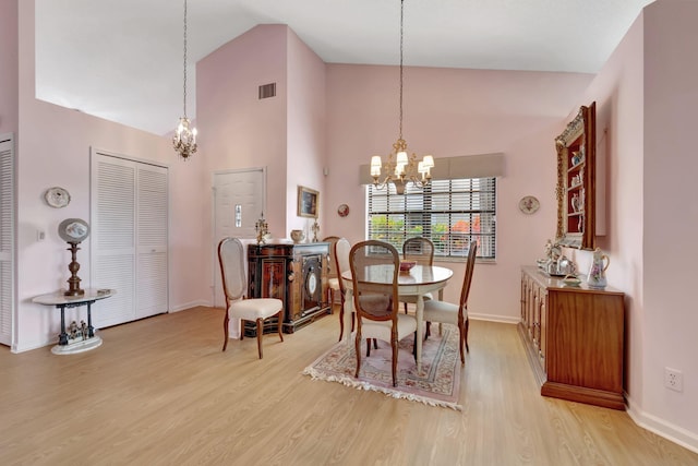 dining space with an inviting chandelier, light hardwood / wood-style floors, and high vaulted ceiling