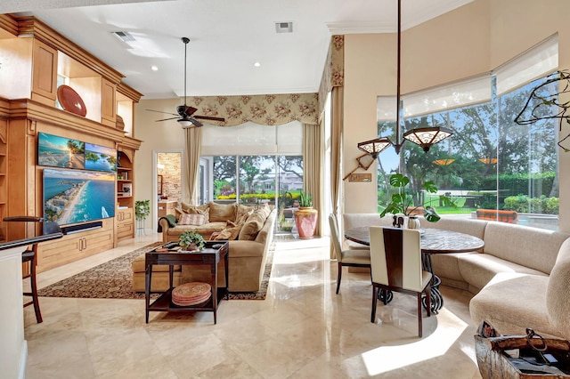 living room with a high ceiling, crown molding, and ceiling fan