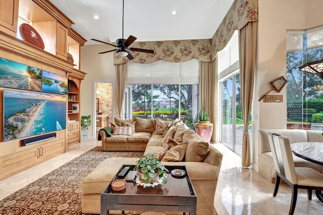 tiled living room featuring a towering ceiling, ornamental molding, and ceiling fan