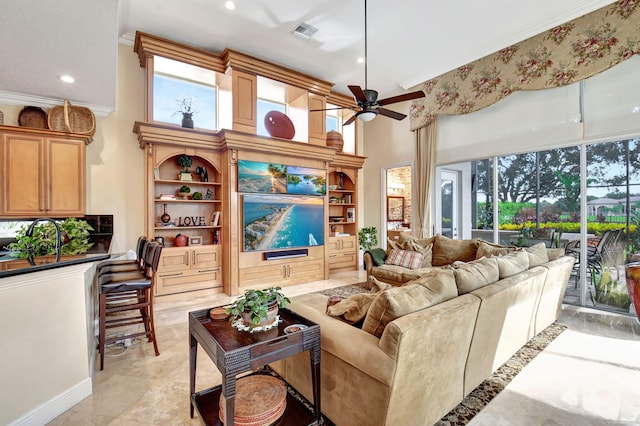 living room with ornamental molding, a high ceiling, and ceiling fan