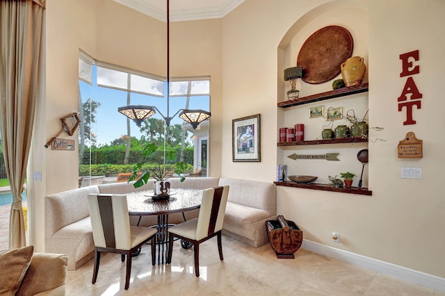 dining area with ornamental molding and a towering ceiling