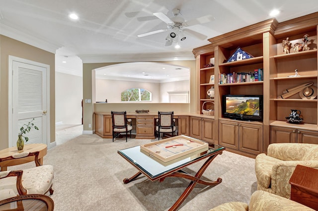 living room featuring light colored carpet, ornamental molding, built in desk, and ceiling fan