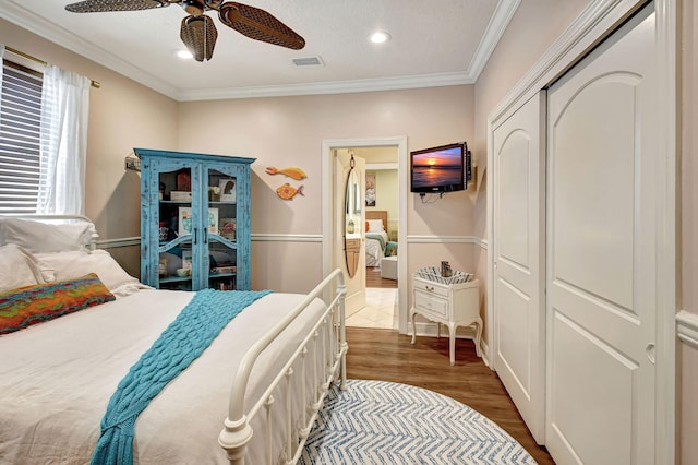 bedroom featuring dark hardwood / wood-style flooring, ornamental molding, a closet, and ceiling fan