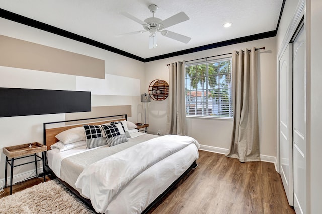 bedroom with hardwood / wood-style flooring, a closet, ornamental molding, a textured ceiling, and ceiling fan