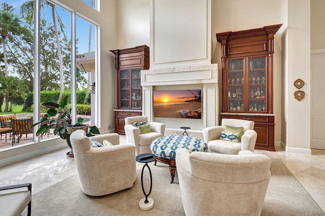 sitting room featuring a towering ceiling and a high end fireplace